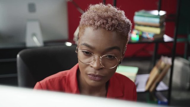 Beautiful smart female employee working on personal computer in office. Portrait of nice-looking businesswoman behind monitor in corporate company.