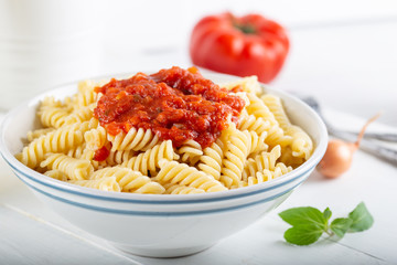 Pasta with tomato sauce on wooden background.