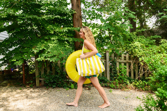 Young woman carrying yellow inflatable and bag