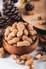 Peanuts in the shell and peeled close up in a wooden cup. Background with peanuts.