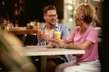 Happy couple talking while drinking cocktails in a bar.