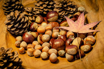 Chestnuts and hazelnuts on a wooden bowl over a wood table
