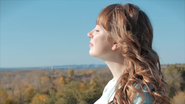 Portrait of a European woman or girl raising her face to the sun. A woman receives vitamin D from the sun