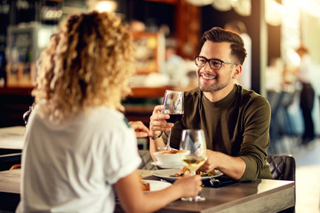 Young happy couple enjoying in conversation while having lunch in a bar.