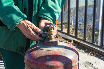 the working man has controlled gas cylinder propane closeup, the background is blurred with bokeh...