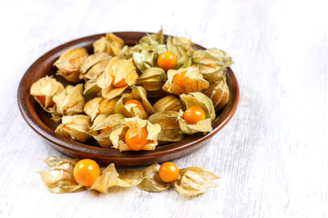 Physalis on a clay dish. Ripe berries of autumn physalis fruit