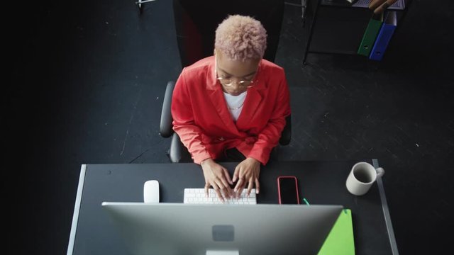Downward view of young business woman keyboarding on personal computer in the office. Tired female employee getting thing done finishing work relaxing in chair.