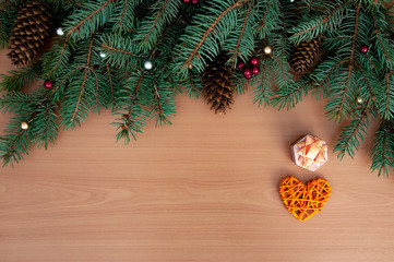 Christmas background. Christmas tree branches, gift, hearts, balls and stars on wooden texture