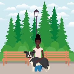 young afro woman lifting cute dog in the field