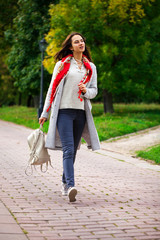 Portrait of a young beautiful girl in blue jeans and gray coat