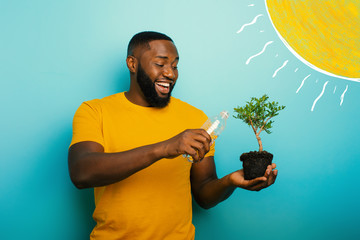 Happy boy watering a small tree ready to be planted. Concept of forestation