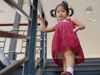 Little baby girl, 42 months old, walking down the stairs by herself, holding on to handrail