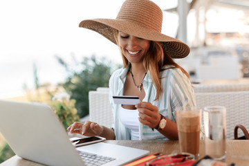 Happy woman e-banking with credit card and smart phone in a cafe.