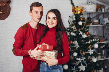 Family in the studio. Brunette near Christmas tree. Couple in a red sweaters
