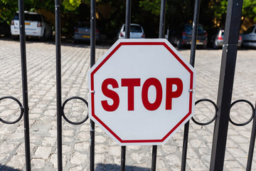 Stop sign on the fence in front of the Parking lot. Close up of a red hexagonal stop sign on a...