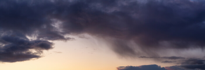 Dramatic Panoramic View of a cloudscape during a dark, rainy and colorful sunset. Taken in Alaska, USA.