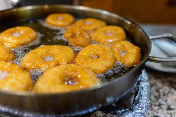The dough is cooked in hot boiling oil. Donuts fry in a pan with hot oil