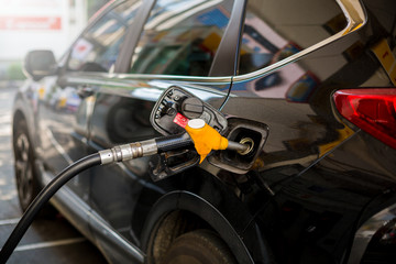 Hand refilling the black car with fuel at the gas station. Oil and gas energy. black car in gas station, refilling the car with fuel at the refuel station, the concept of fuel energy, selective focus.