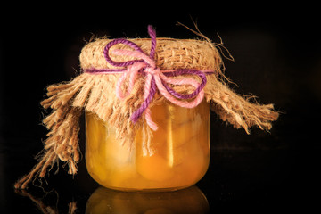 closeup single small glass jar of delicious yellow fruit jam
