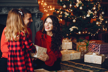 Beautiful mother in a red sweater. Family sitting near christmas gifts. Little girl and boy near christmas tree