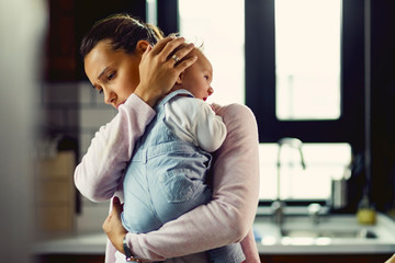 Affectionate mother consoling her baby at home.