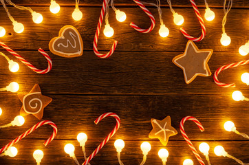 Christmas background. Gingerbread cookies, christmas candy and holiday decorations frame on wooden boards. Top view with copy space for text