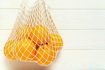 Oranges in a white mesh reusable bag