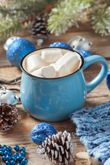 Christmas toys and a mug of coffee with fluffy white marshmallow on a wooden table.