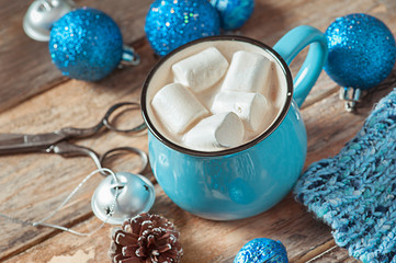 Christmas toys and a mug of coffee with fluffy white marshmallow on a wooden table.