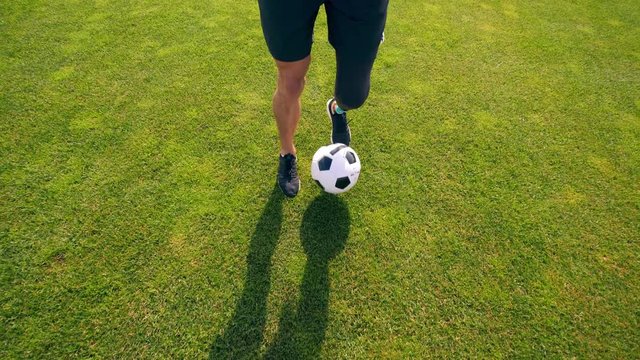Green lawn with a physically challenged man playing soccer, football
