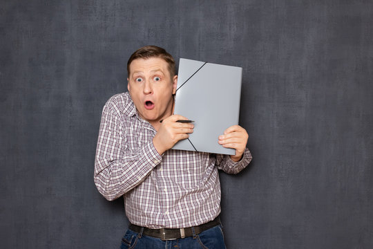 Portrait Of Surprised Shocked Man Looking From Behind Folder