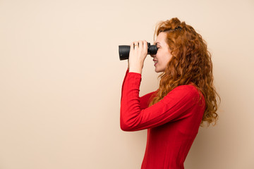 Redhead woman with turtleneck sweater with black binoculars