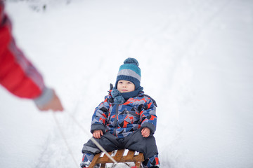 Fototapeta na wymiar Little boy on a sledge at winter day