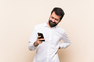 Young man with beard holding a mobile suffering from backache for having made an effort