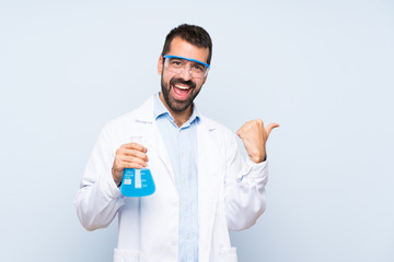 Young scientific holding laboratory flask over isolated background with thumbs up gesture and smiling