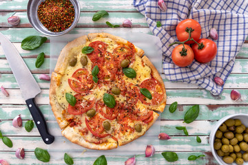 Freshly made wood fired pizza viewed from above on rustic turquoise boards