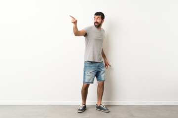 A full-length shot of handsome man with beard pointing away