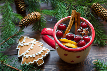 Mulled wine In porcelain mug with berries, cinnamon sticks and star anise on brown wood table with...