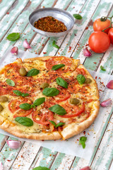 Freshly made wood fired pizza viewed from above on rustic turquoise boards