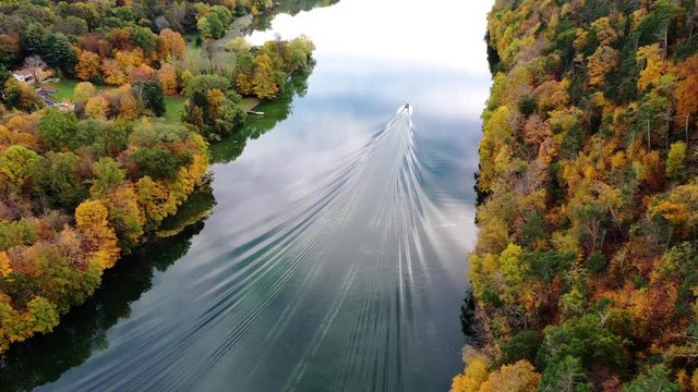 Beautiful autumn scene of boat on river with colorful fall foliage