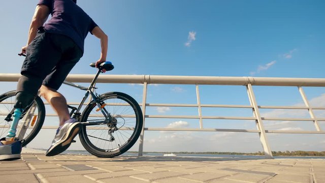 A man with an imitated leg is walking away with the bike
