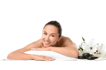 Beautiful woman with spa supplies lying on towel against white background