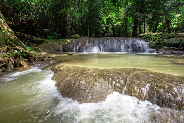 The natural background of waterfalls that blur the flow of water, with various tree species surrounded and boulders of various sizes, the beauty of the ecosystem and the jungles of forests.