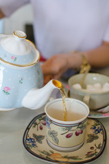 Pouring tea from vintage teapot to the cup. British tea time.