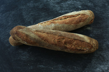 Baguette . Fresh homemade bread. long rectangular bread baguette on a dark background. Mother dough bread. Loaves of bread lie in rows