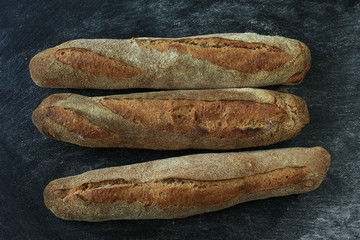 Baguette . Fresh homemade bread. long rectangular bread baguette on a dark background. Mother dough bread. Loaves of bread lie in rows