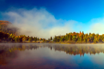 Lake fog panorama with autumn foliage and mountains with reflection.
