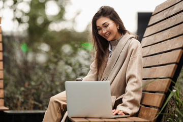Beautiful girl lawyer Asian appearance with a smile looking through the working contract on his laptop sitting in the autumn Park.