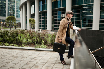Fototapeta premium A grown man, in classic autumn clothes, thoughtfully looks into the distance with a business contract in his hand