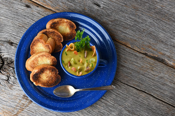 Split Pea soup with garlic toast on a rustic wood table with copy space.
